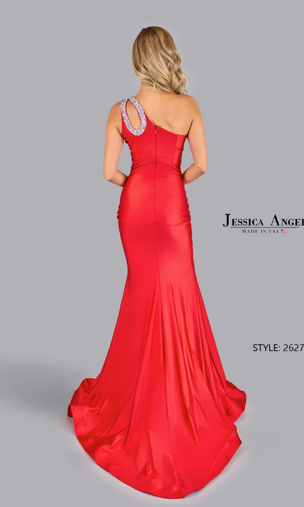 A woman models the Jessica Angel 2627 One-Shoulder Cut-Out Prom Gown, a fitted, floor-length dress with rhinestone loop detail, shown from the back against a plain gray background.